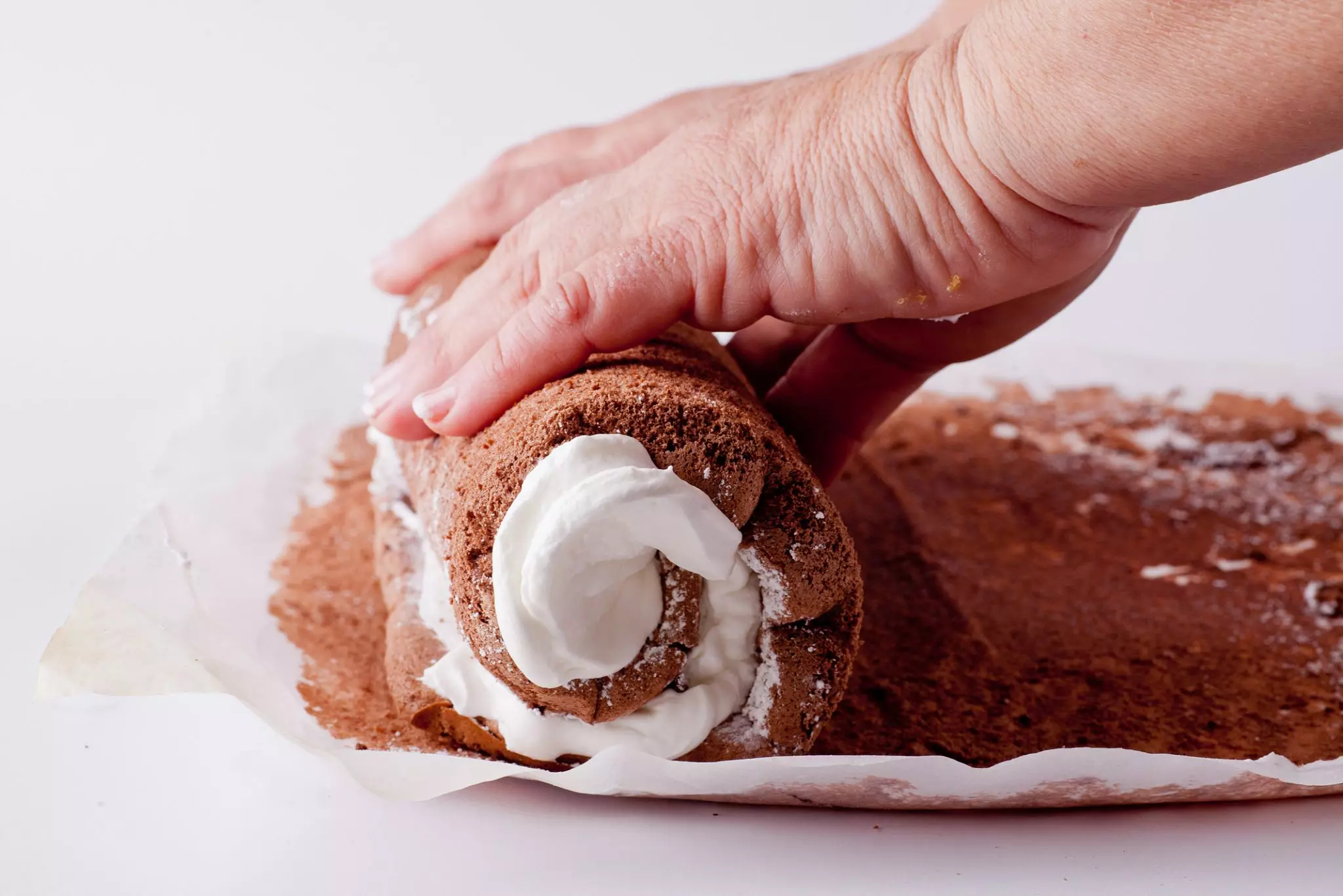 פותחים את הרולדה ומסירים את הנייר בזהירות. מורחים כמחצית מהקרם על יריעת הבצק ומגלגלים שוב