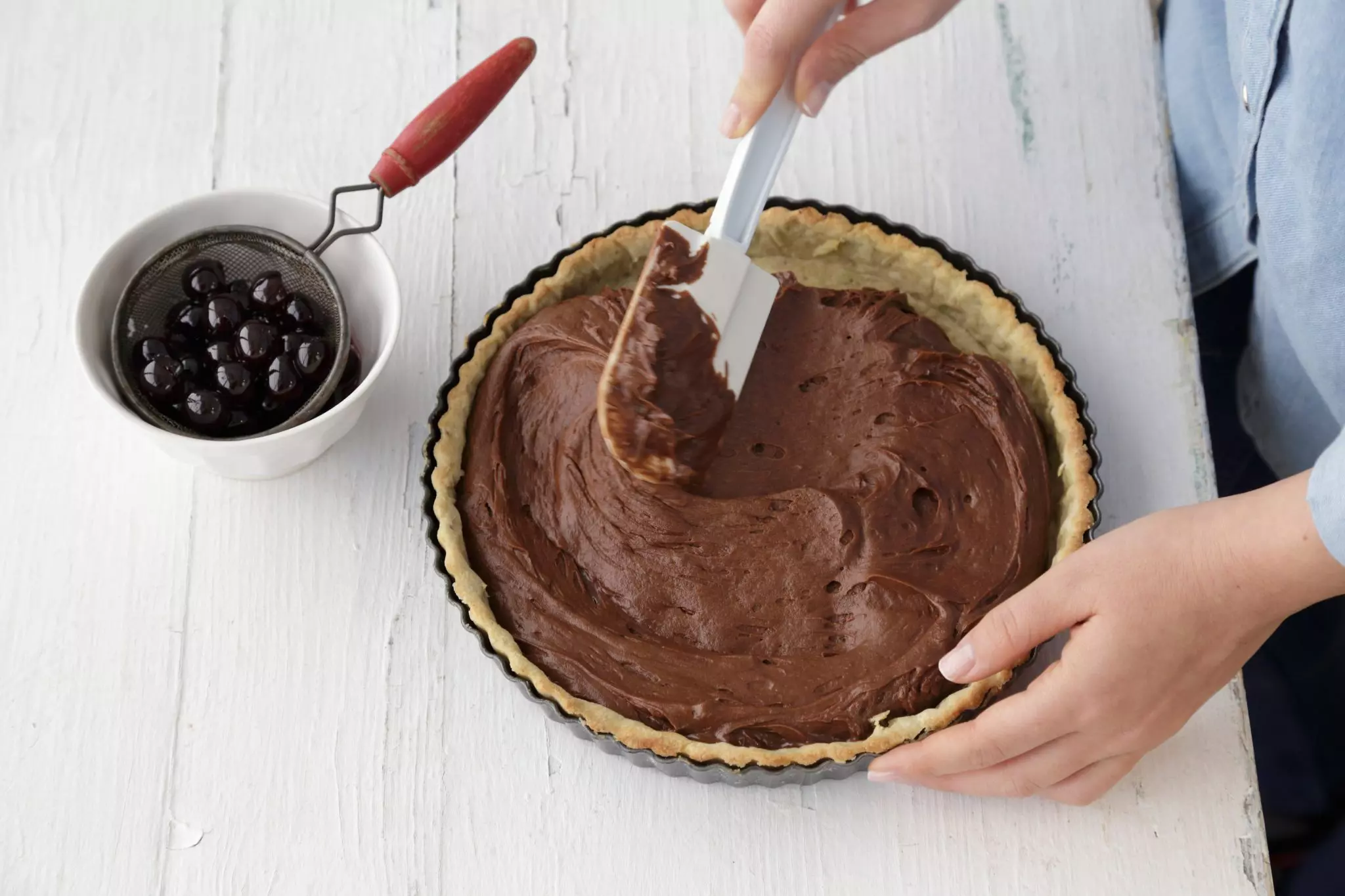 יוצקים את תערובת השוקולד על הקלתית החצי-אפויה ומיישרים.