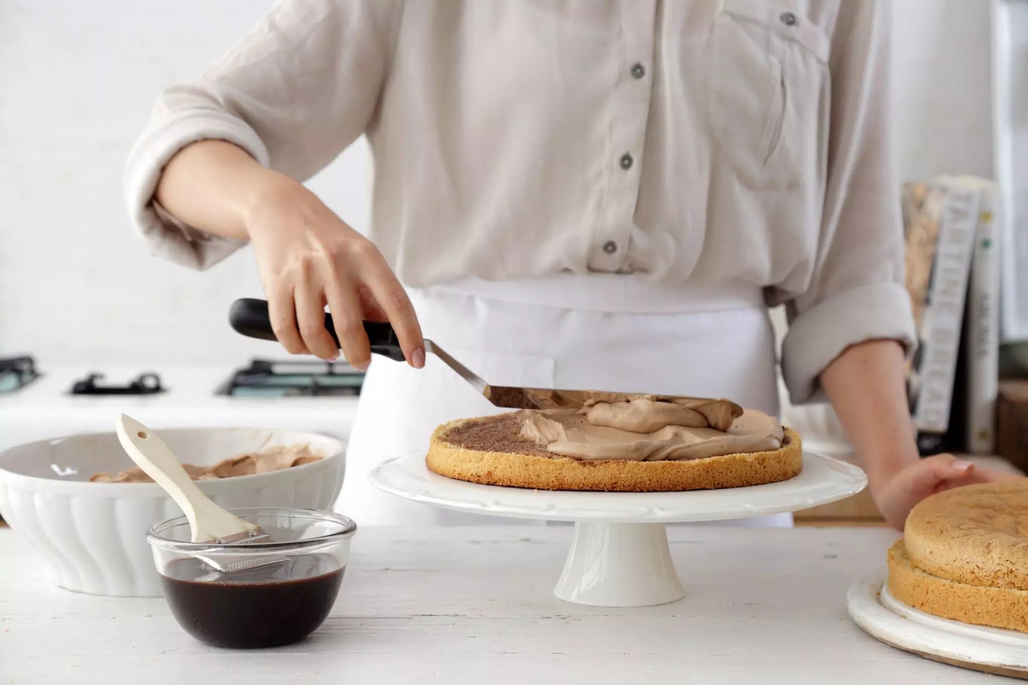 מניחים שכבה אחת על צלחת הגשה. מברישים בנדיבות בסירופ ויוצקים בערך 1/4 מכמות הקרם. משטחים בעזרת פלטה.