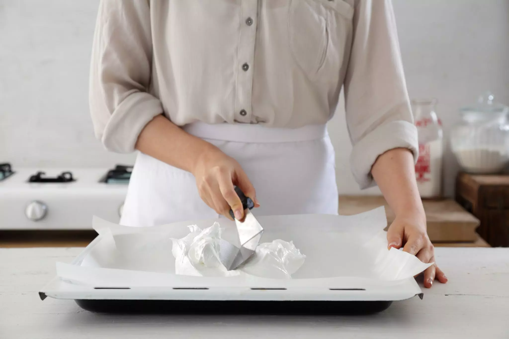 מעבירים את התערובת לתבנית תנור מרופדת בנייר אפייה ובעזרת לקקן או כף יוצרים צורה של פבלובה