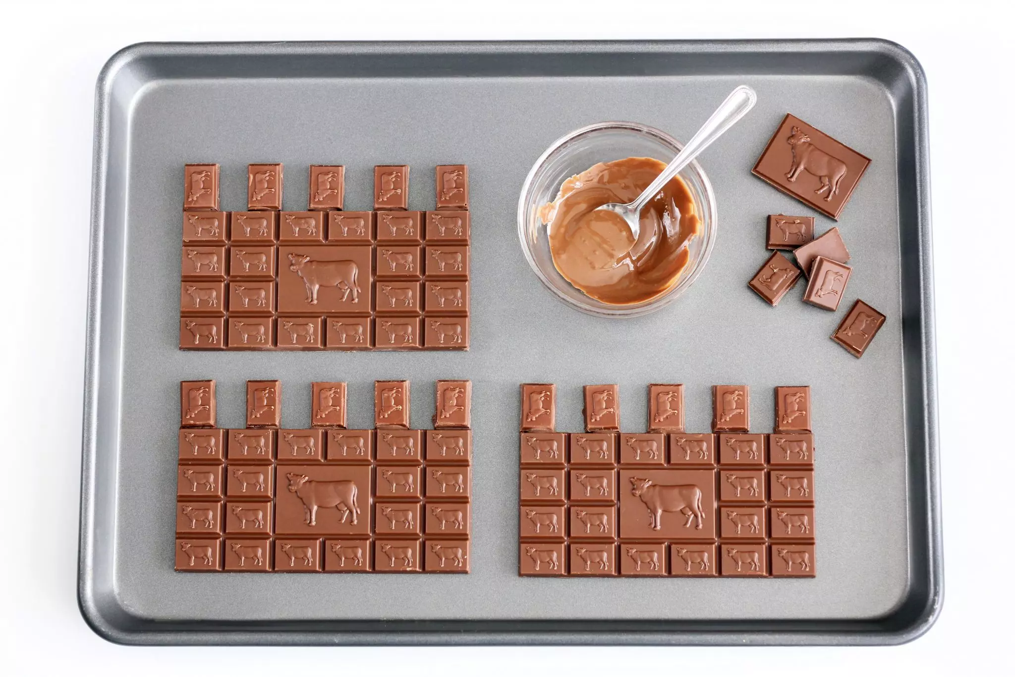 עוגת יום הולדת טירה - עיטור, מניחים על תבנית מרופדת בנייר אפייה 4 חפיסות שלמות של שוקולד חלב, עבור הקירות.