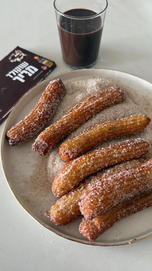 ⁨	ה-מתכון שלכם לחנוכה - צ’ורוס זהובים, קראנצ׳יים מבחוץ ואווריריים מבפנים, שהכי טעים להגיש לצד רוטב שוקולד חם. באמת שאין ביס מופלא כזה💕
איך מכינים?
לצ׳ורוס:
1 כוס (240 מ״ל) חלב
 1/4 כוס (50 גרם) סוכר 
100 גרם חמאה 
1 כוס (140 גרם) קמח 
2-3 ביצים L 
קורט מלח 
שמן - לטיגון
לציפוי:
1/4 כוס סוכר 
1 כף קינמון טחון 
לרוטב שוקולד:
100 גרם שוקולד פרה מריר (אפשר גם חלב או לבן)
125 מ״ל (1/2 מיכל) שמנת מתוקה 

אופן ההכנה:
- בסיר קטן על אש גבוהה שמים יחד חלב, מלח, סוכר וחמאה ומביאים לרתיחה חזקה. חשוב לוודא שכל החמאה נמסה.
ברגע שהתערובת רותחת, מסירים מהאש ומוסיפים בבת אחת הקמח.
- בעזרת כף עץ מערבבים את התערובת עד שנוצר בצק חלק ואחיד שנפרד מדפנות הסיר.
- מעבירים את הבצק לקערת מיקסר עם וו גיטרה ומעבדים 2-3 דקות, עד שהוא מעט מתקרר.
- מוסיפים ביצה אחת ומערבלים עד שהיא נטמעת בבצק. מוסיפים ביצה נוספת וממשיכים לעבד את הבצק עד שהוא מתאחד.
- לפני שמוסיפים את הביצה השלישית בודקים את הבצק מוכן על ידי לקיחה של כמות קטנה בין 2 אצבעות – אם נוצר מעין “חוט” בצק, זה סימן שהבצק מוכן ואין צורך להוסיף ביצה. אם לא, מוסיפים עוד 1/2 ביצה טרופה בהדרגה וממשיכים לערבל עד שאחיד ובודקים שוב.
- כאשר הבצק מוכן מעבירים לשק זילוף עם צנתר משונן.
בינתיים מחממים שמן עמוק בתוך סיר טיגון.
- מזלפים בצק בגודל 6-7 ס״מ לתוך השמן הרותח בעדינות ומטגנים היטב.
- לאחר שהצ’ורוס זהובים משני הצדדים מוציאים אותם אל נייר סופג בעזרת כף מחוררת.
- ציפוי: בקערה מערבבים יחד סוכר עם מעט קינמון, ומגלגלים את הצ’ורוס החמים בתערובת הסוכר.
- רוטב שוקולד: ממיסים שוקולד ושמנת במיקרו בפולסים ומערבבים לתערובת אחידה.
- מגישים יחד ואוכלים חם.⁩